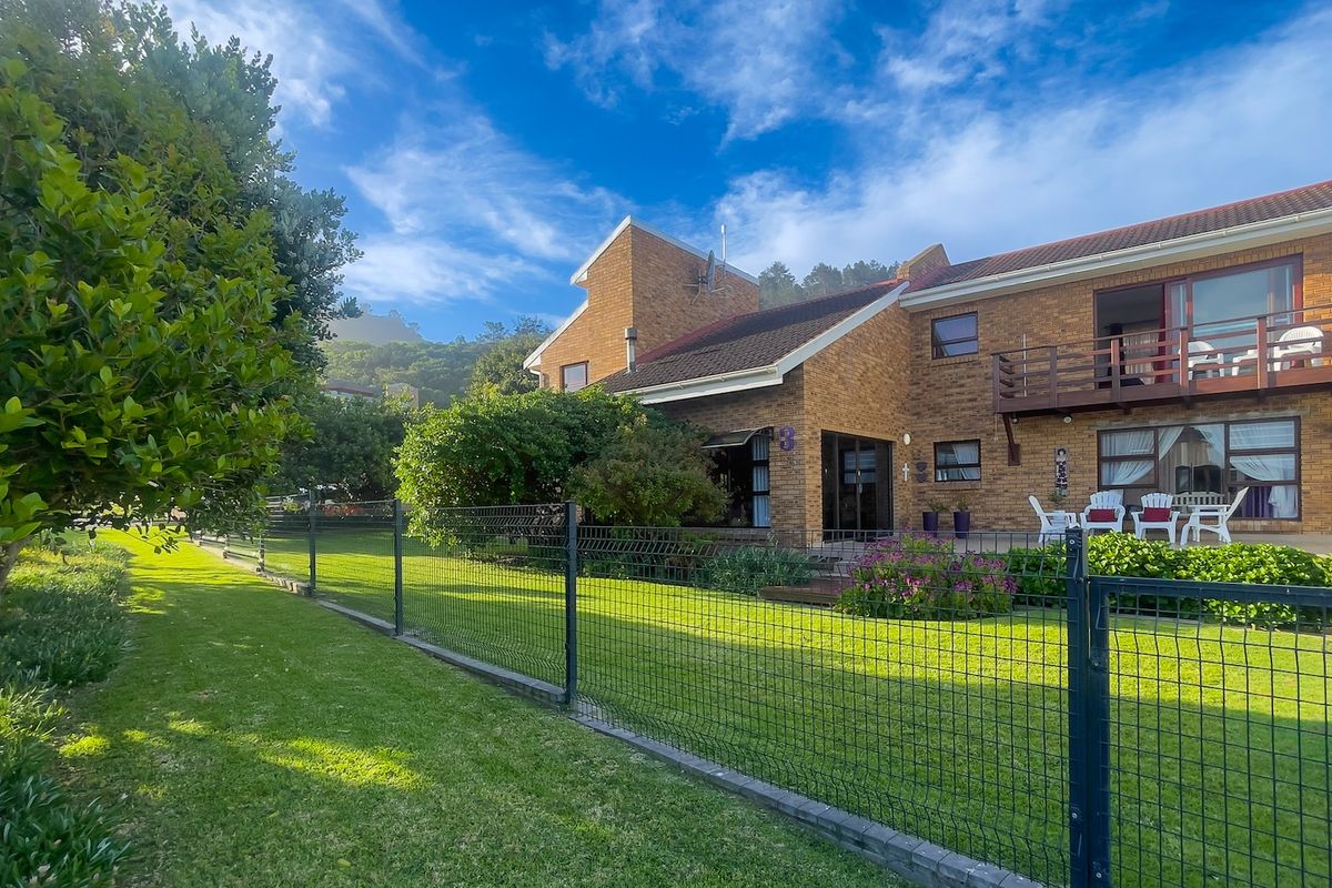 A well-maintained double-story face brick home featuring a spacious rear garden, paved patio, and an upper-level balcony overlooking the lawn.