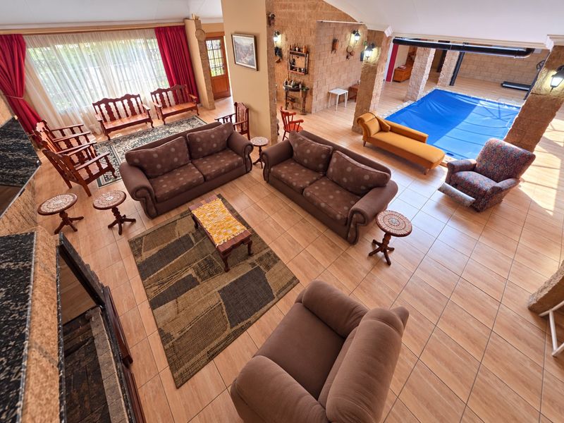 Spacious open-plan living area featuring tiled floors, a stone feature wall, vaulted ceilings, and a unique integrated indoor swimming pool.