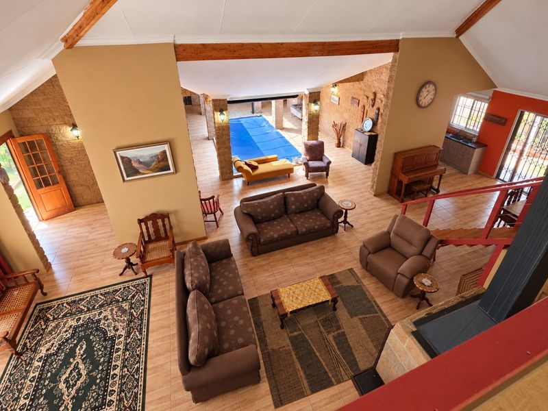 Spacious open-plan living area featuring vaulted ceilings with exposed beams, stone accents, tiled floors, a fireplace, and an integrated indoor swimming pool.