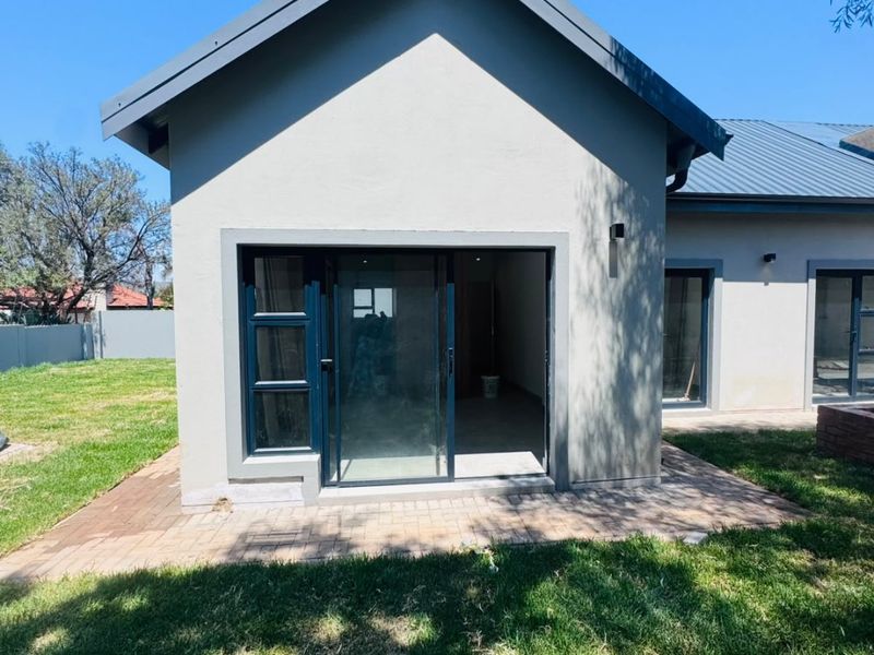 Rear view of the property featuring a paved patio area, sliding glass doors, and a well-maintained lawn.