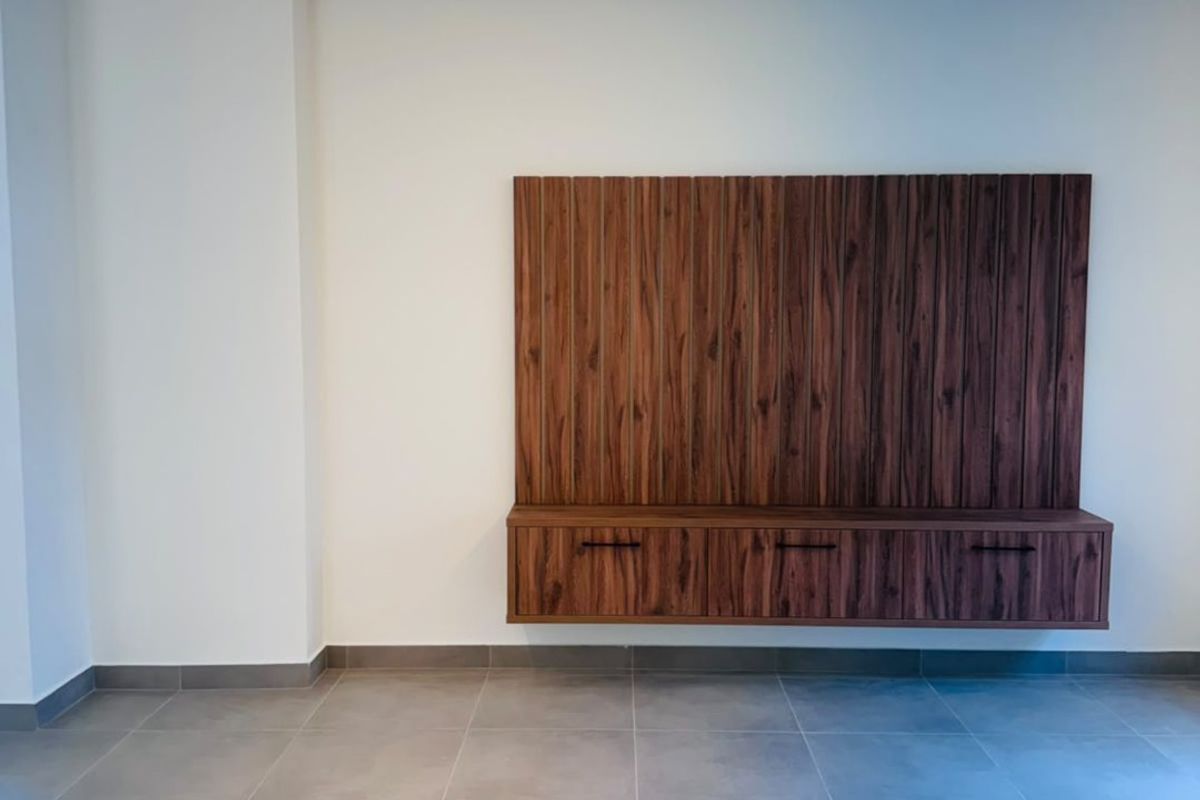 A modern, minimalist living area featuring large format floor tiles, a sleek built-in wooden media console, and recessed ceiling lighting.