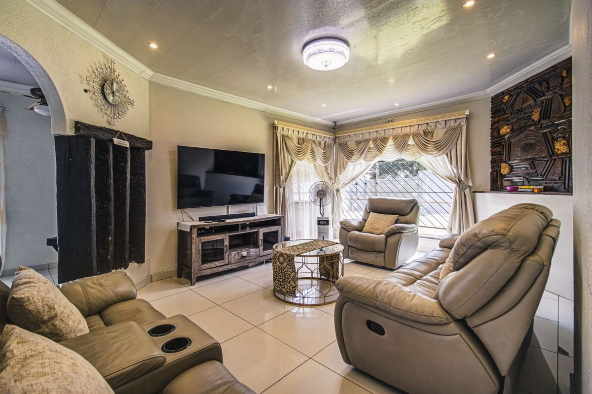 A comfortable living room featuring tiled flooring, recessed lighting, and a decorative stone wall element, providing a functional and well-lit space.