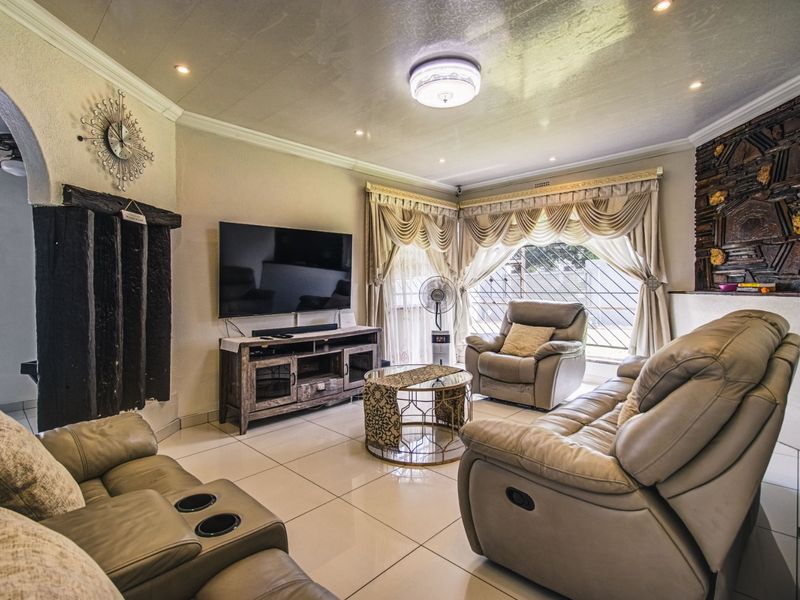 A comfortable living room featuring tiled flooring, recessed lighting, and a decorative stone wall element, providing a functional and well-lit space.