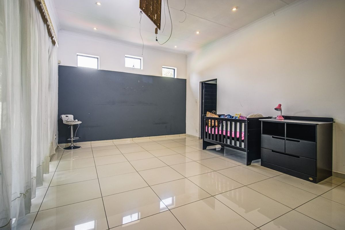 Spacious bedroom featuring large format floor tiles, a dark accent wall, and high-level clerestory windows, requiring minor electrical finishing.