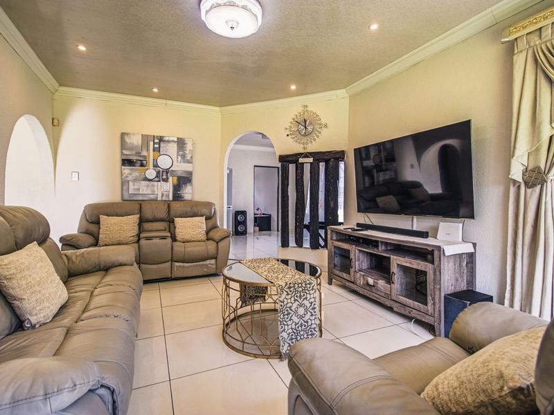 A comfortable living room featuring tiled flooring, recessed downlighting, and an elegant archway leading to adjacent living spaces.