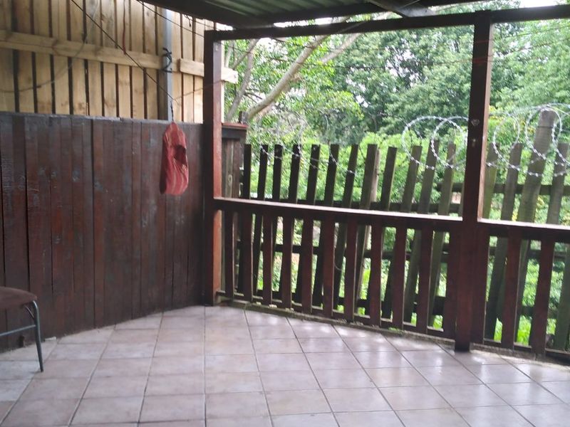A covered outdoor patio area featuring tiled flooring and timber perimeter fencing, providing a functional space for outdoor relaxation.