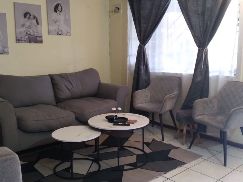 A comfortable living room area featuring tiled flooring and a large window, providing a functional and well-lit space for relaxation.