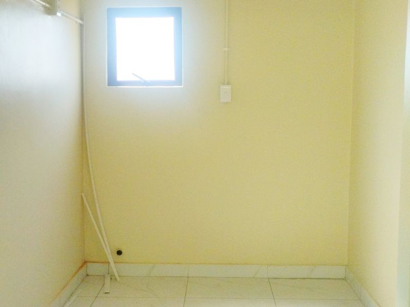 A small, empty utility space featuring tiled flooring and a single window, suitable for storage or laundry conversion.