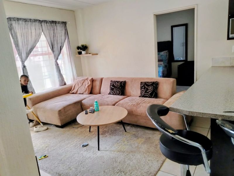 Open plan living area featuring a breakfast bar, tiled flooring, and access to an adjacent bedroom, requiring minor cosmetic updates to improve presentation.