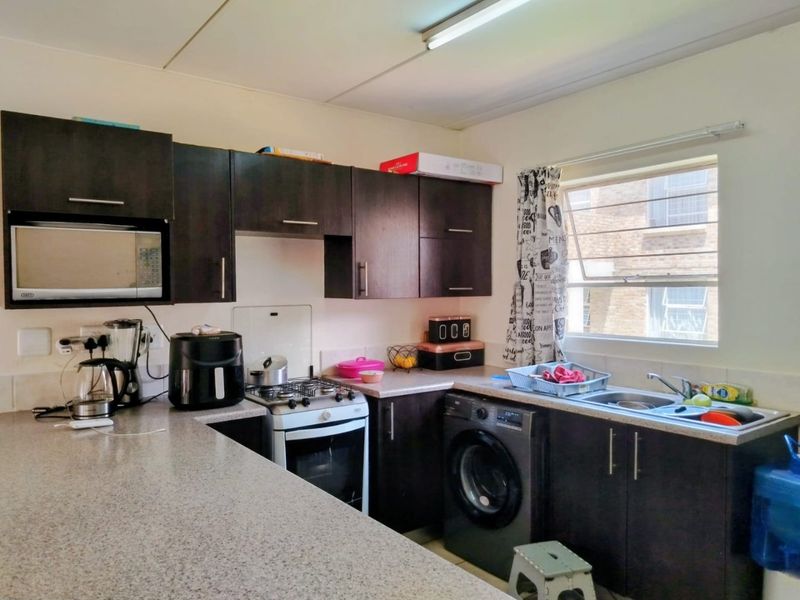 Functional kitchen featuring dark wood cabinetry, laminate countertops, a gas stove, and integrated space for a washing machine.