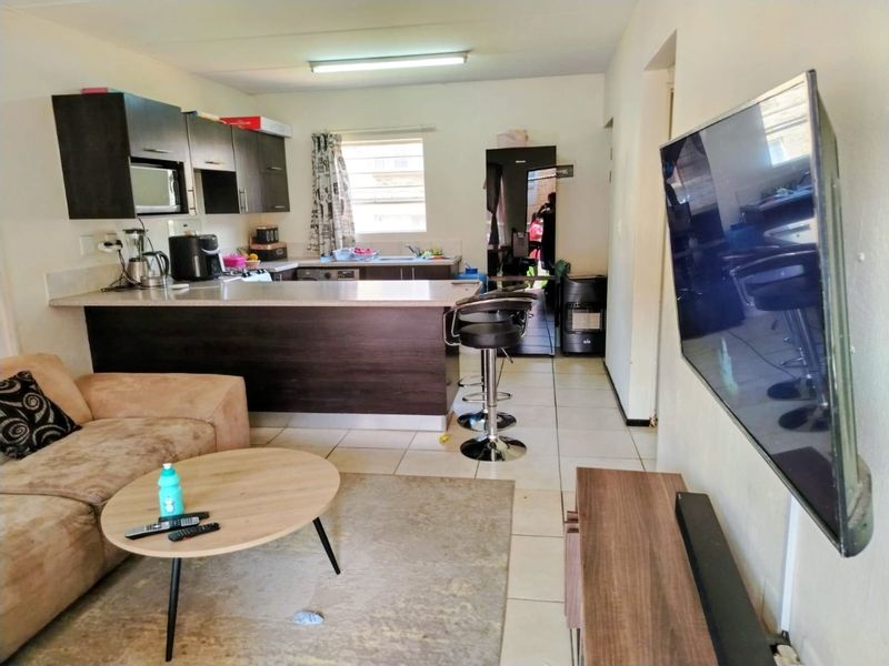 Open-plan living and kitchen area featuring dark wood cabinetry, a breakfast bar, and tiled flooring throughout.