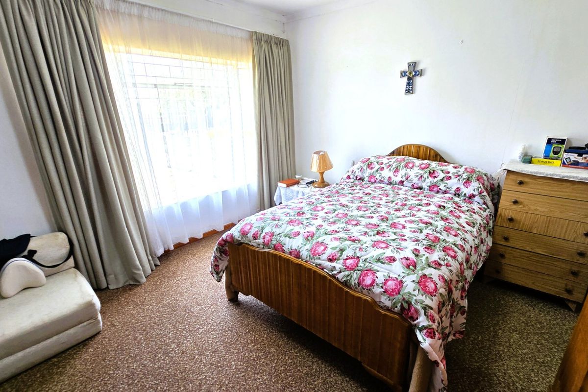 A standard bedroom featuring carpeted flooring and large windows with curtain tracks, offering a functional space with neutral wall finishes.