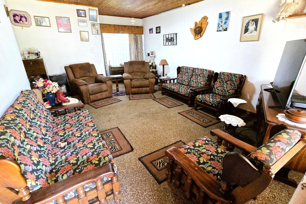 A spacious living room featuring a timber-clad ceiling and carpeted flooring, offering a comfortable and traditional layout.