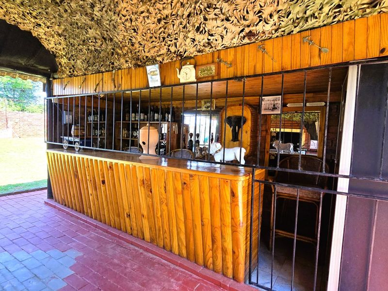 Outdoor entertainment area featuring a built-in wooden bar counter, brick paving, and secure metal gating, ideal for social gatherings.