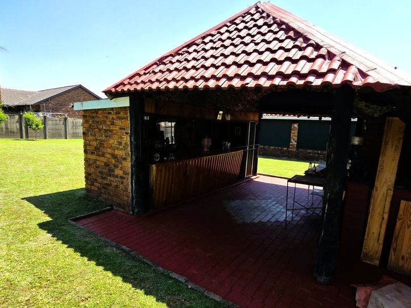 Outdoor entertainment area featuring a built-in bar, brick chimney, and covered patio space overlooking the garden.