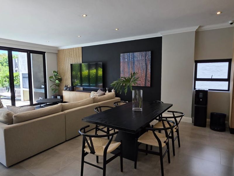 Spacious open-plan living and dining area featuring large format floor tiles, modern recessed lighting, and seamless access to the outdoor patio through sliding glass doors.