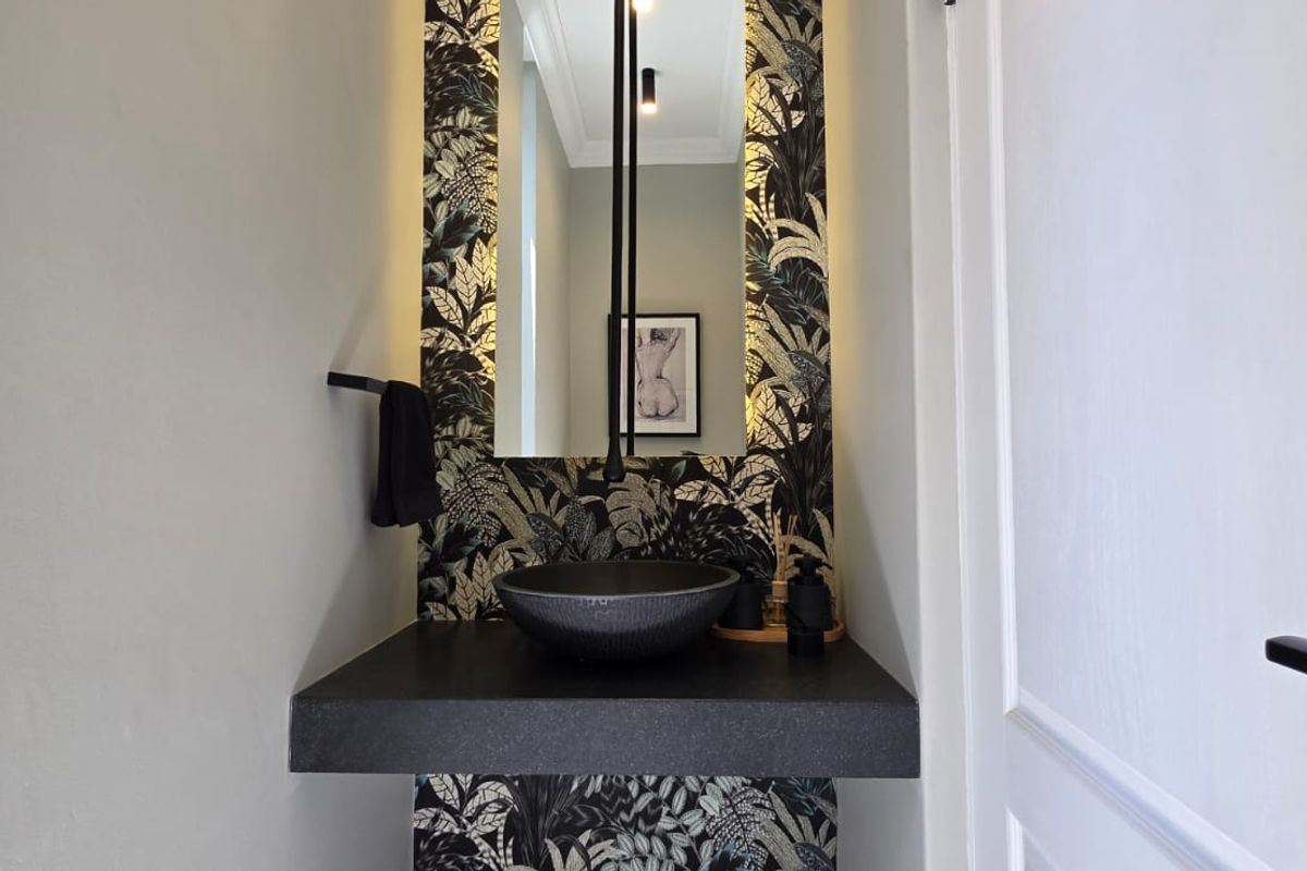 A modern powder room featuring a floating vanity, striking vessel sink, wall-mounted faucet, and decorative backlit wallpaper.