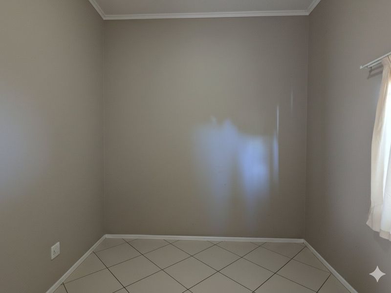 A vacant bedroom featuring neutral wall paint, tiled flooring, and a fitted curtain rail, offering a clean and versatile space ready for personalization.