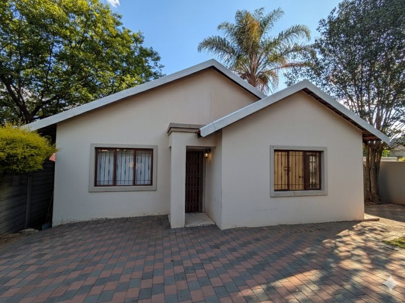 Front elevation of a single-story house featuring a paved driveway, security-fitted windows, and a covered entrance.