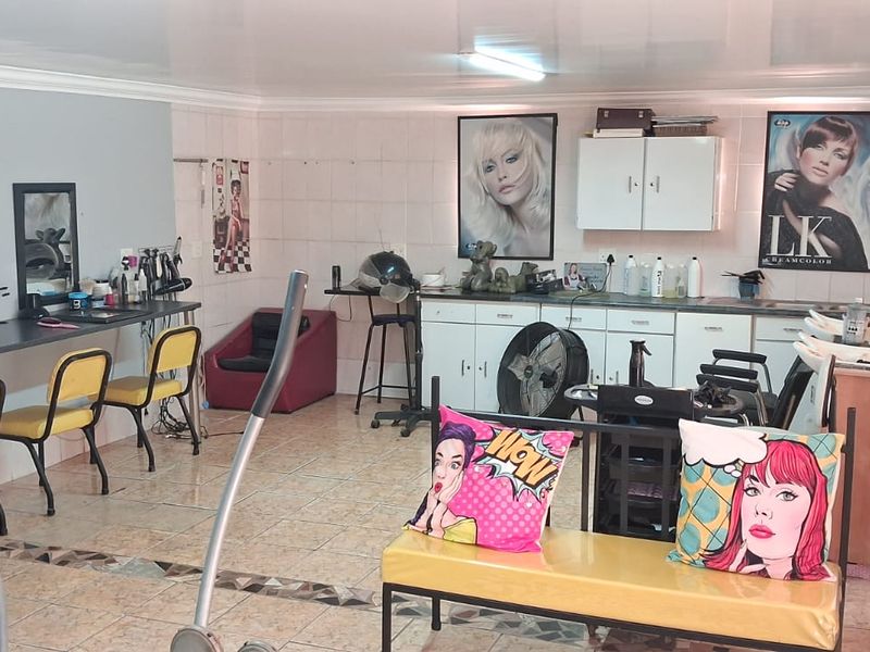A functional utility space currently configured as a salon, featuring tiled flooring, built-in cabinetry, and wall-mounted mirrors.