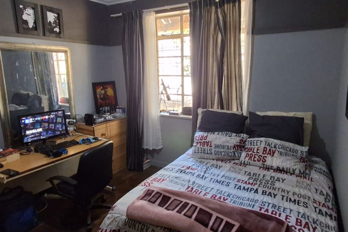 A functional bedroom featuring timber flooring and a window with natural light, providing a comfortable space for rest or study.