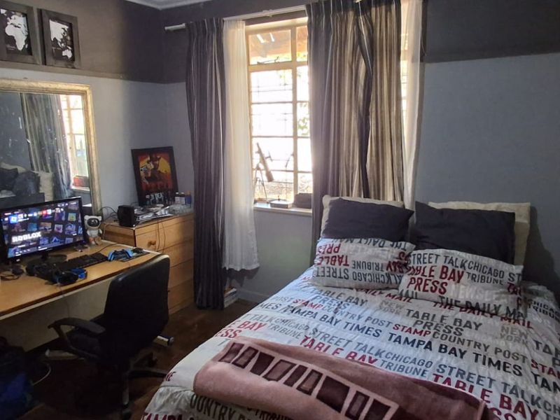 A functional bedroom featuring timber flooring and a window with natural light, providing a comfortable space for rest or study.