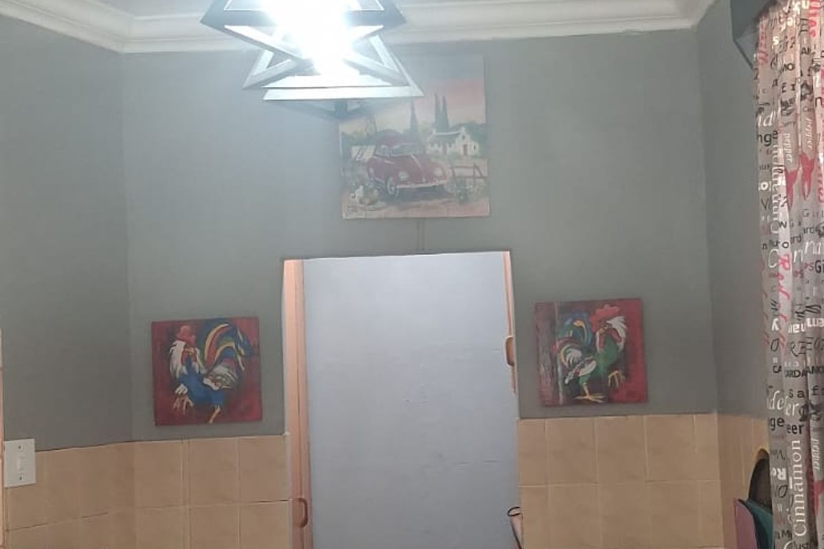 A functional kitchen featuring a built-in stove, double sink, tiled splashback, and modern pendant lighting, offering a practical layout for daily meal preparation.