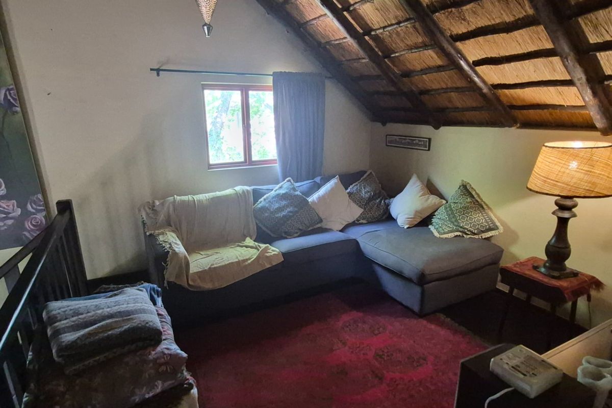 A cozy living room area featuring a unique thatched roof with exposed timber rafters and a metal balustrade overlooking the lower level.