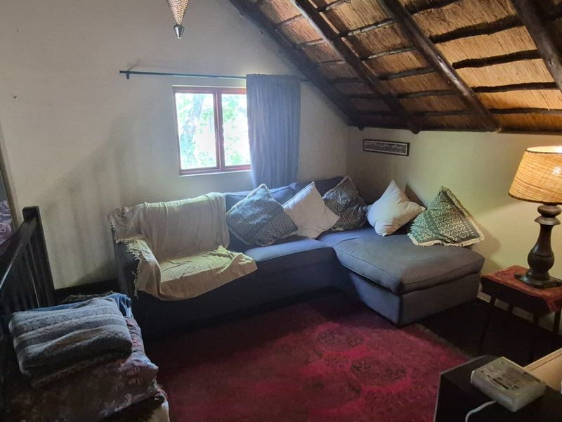 A cozy living room area featuring a unique thatched roof with exposed timber rafters and a metal balustrade overlooking the lower level.