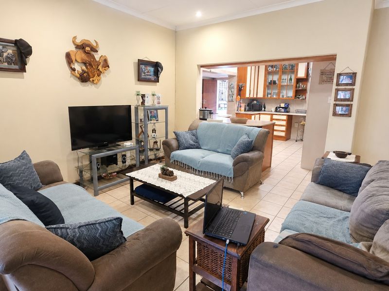Open plan living area featuring tiled flooring and a direct view into the adjacent kitchen with built-in cabinetry and island.