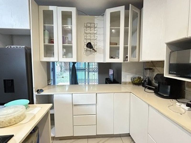 A functional kitchen featuring white cabinetry, stone countertops, and built-in appliances, offering a clean layout with potential for modern updates.