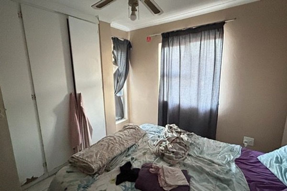 A bedroom featuring a built-in wardrobe with visible wear and a ceiling fan, offering a functional space with potential for cosmetic updates.