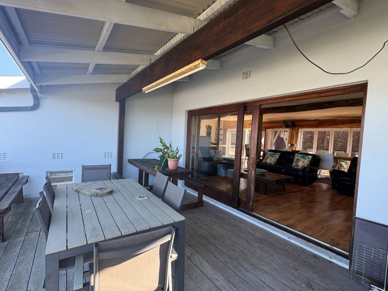 Covered outdoor patio featuring timber decking and large sliding glass doors providing seamless access to the interior living area.