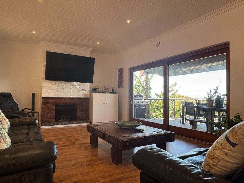 Spacious living room featuring a brick fireplace, wood-look flooring, and large sliding glass doors that open onto an outdoor patio area.