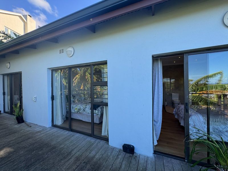 A wooden deck patio area featuring sliding glass doors providing access to the interior living spaces of the home.