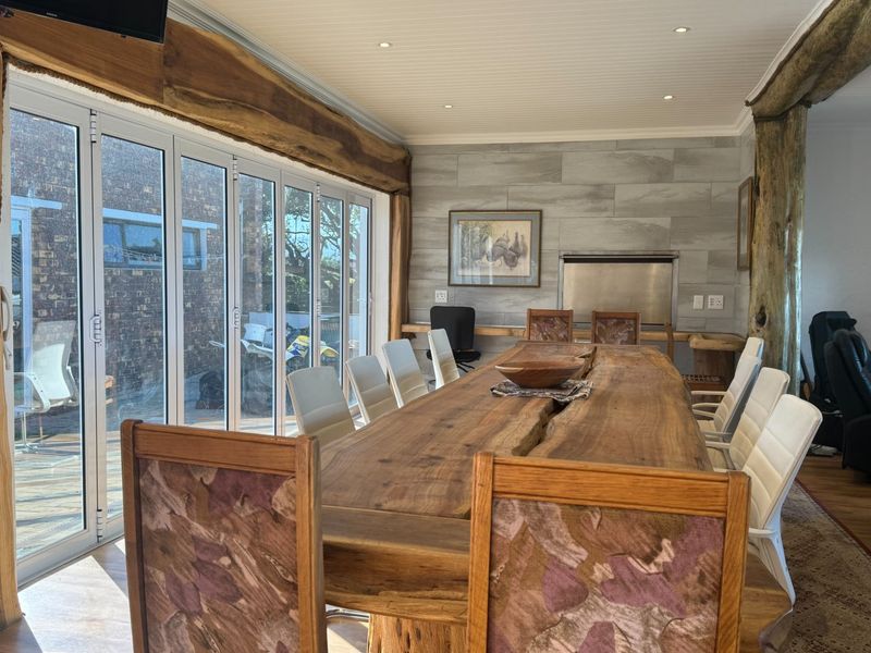 Spacious dining area featuring a large timber table, built-in fireplace, and expansive bi-fold glass doors that provide seamless access to the outdoor area.