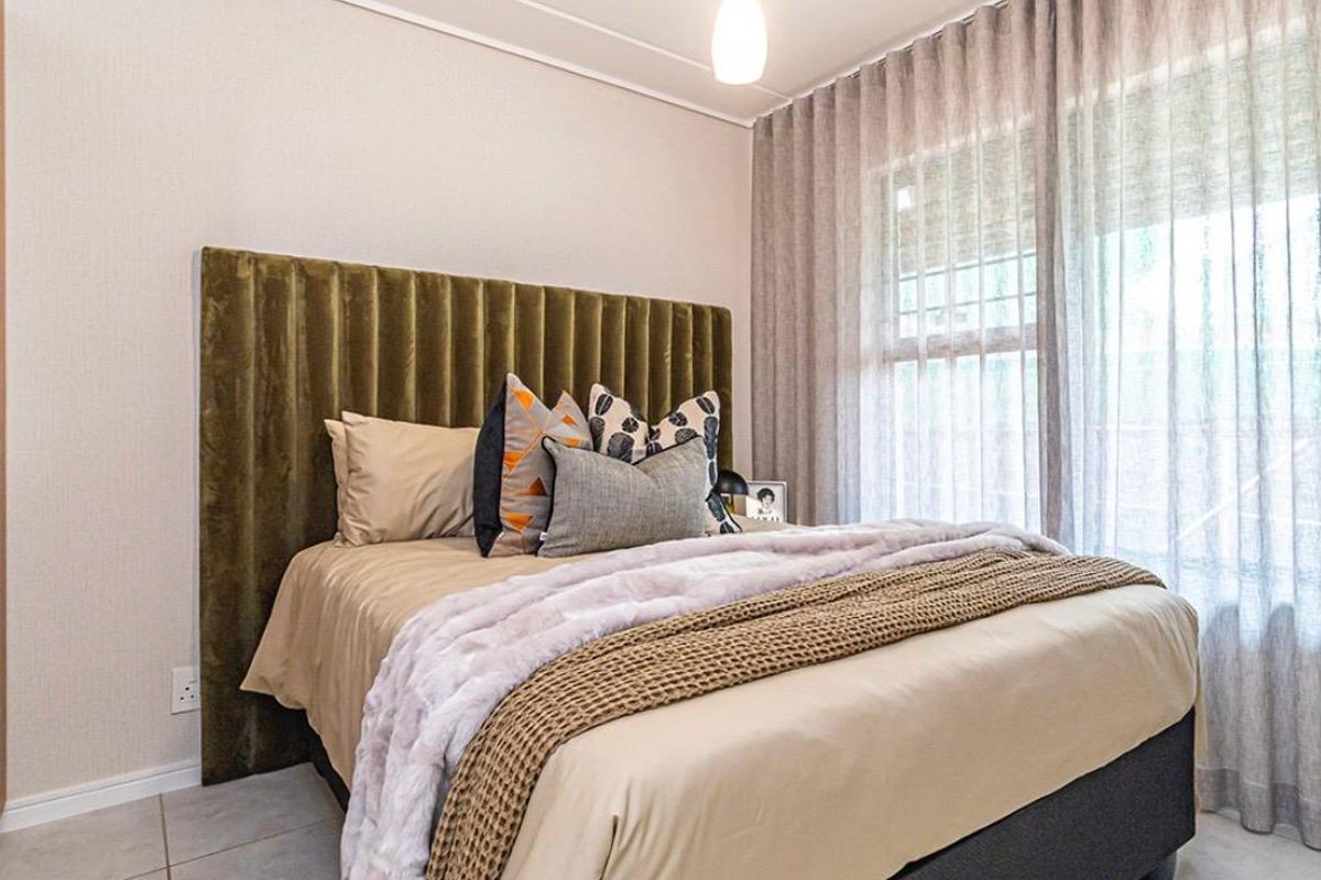 A well-maintained bedroom featuring tiled flooring, neutral wall finishes, and large windows with installed curtain tracks, providing a bright and comfortable living space.