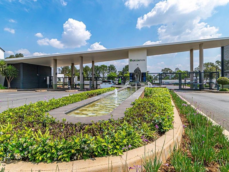 The main entrance to Greenpark estate featuring a modern security gatehouse, landscaped gardens, and a decorative water feature.