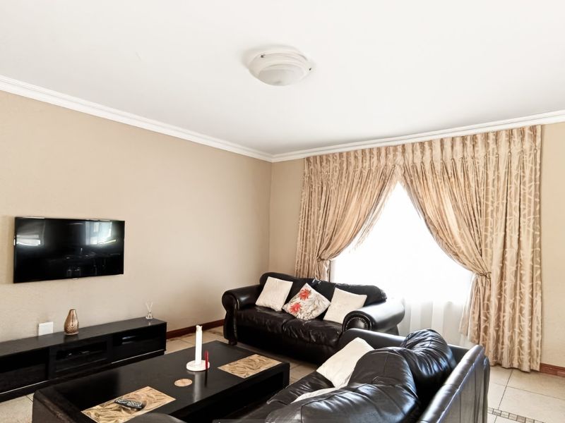 A comfortable living room featuring neutral wall tones, tiled flooring, and classic ceiling cornicing, providing a functional and inviting space for relaxation.