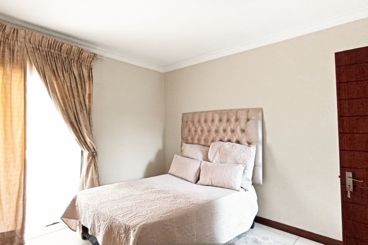 A well-maintained bedroom featuring neutral wall finishes, tiled flooring, and decorative cove cornicing, providing a clean and comfortable living space.
