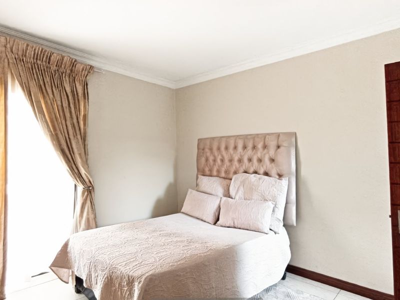 A well-maintained bedroom featuring neutral wall finishes, tiled flooring, and decorative cove cornicing, providing a clean and comfortable living space.