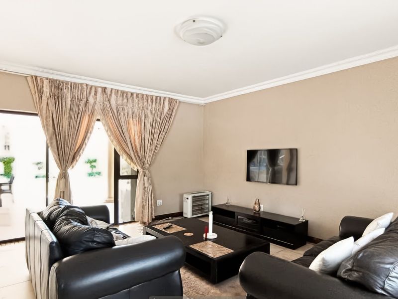 A comfortable living room featuring tiled flooring, neutral wall finishes, and a large sliding glass door providing access to the outdoor patio area.