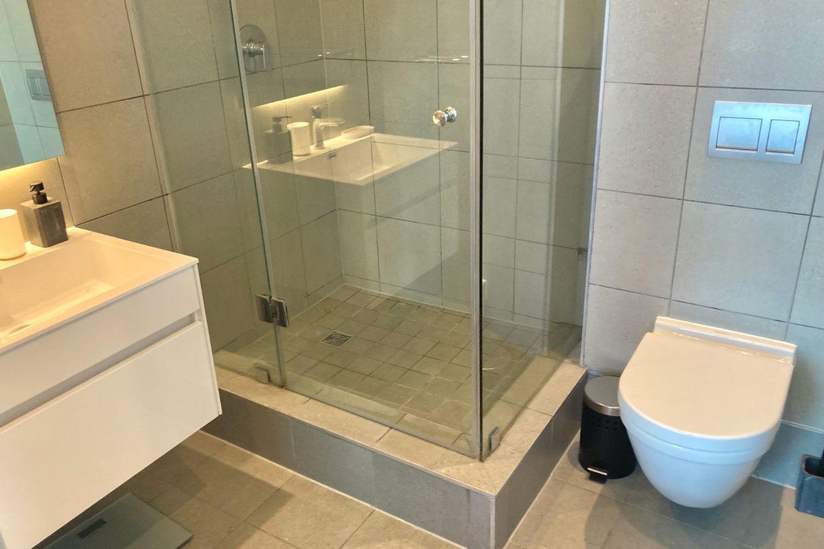 Modern bathroom featuring a wall-mounted vanity, a glass-enclosed shower, and a wall-hung toilet with a concealed cistern.