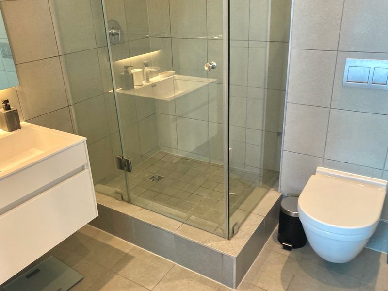 Modern bathroom featuring a wall-mounted vanity, a glass-enclosed shower, and a wall-hung toilet with a concealed cistern.