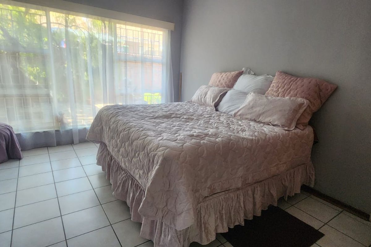 A bedroom featuring tiled flooring and a large window allowing natural light, providing a functional space for rest.