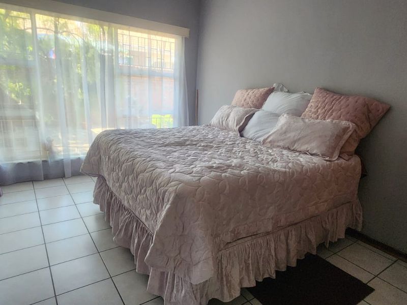 A bedroom featuring tiled flooring and a large window allowing natural light, providing a functional space for rest.