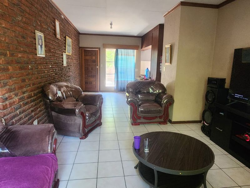 Spacious living area featuring an exposed brick wall, ceramic tiled flooring, and direct access to the outdoor area through a sliding glass door.