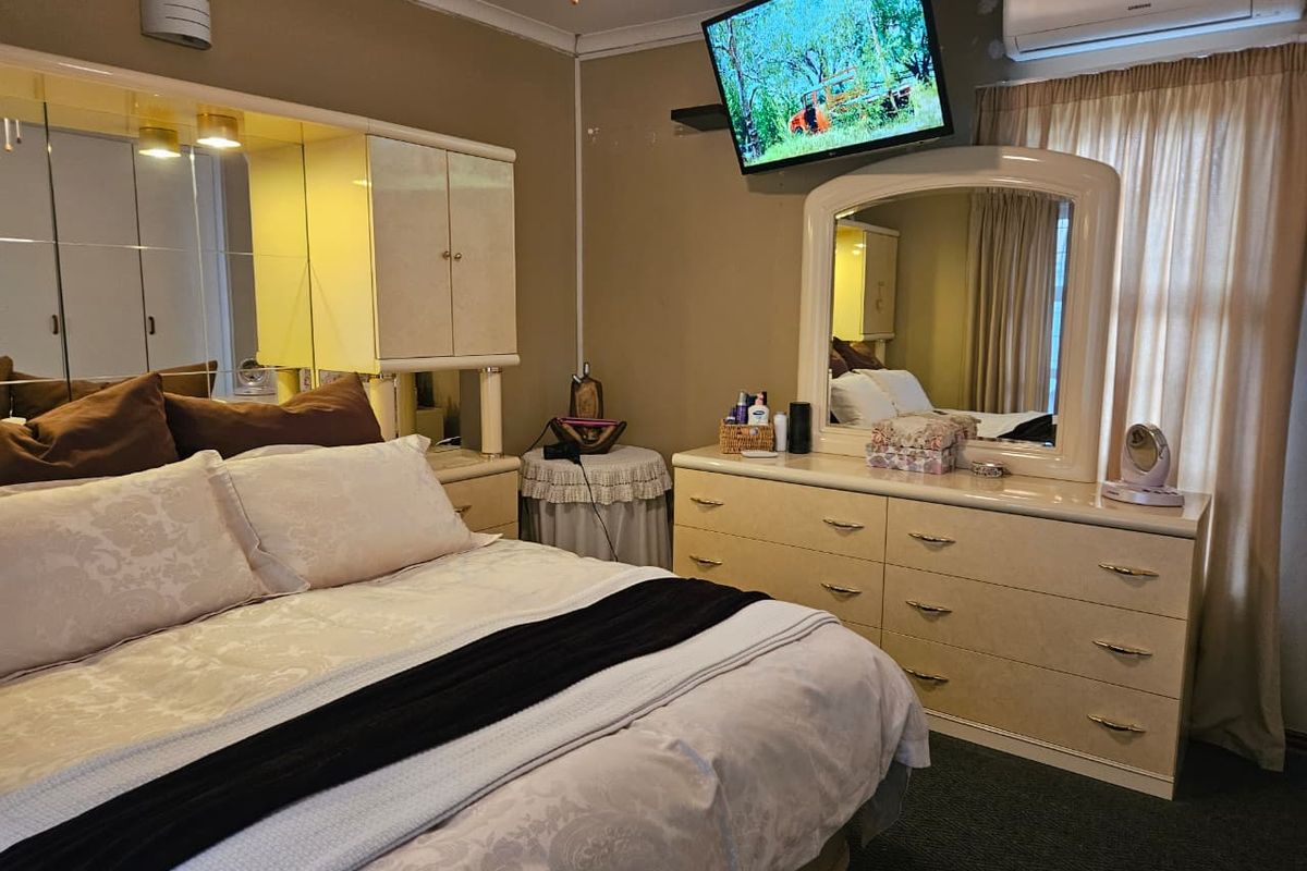 A bedroom featuring built-in cabinetry, wall-mounted air conditioning, and neutral wall finishes, offering a functional space with potential for modern updates.
