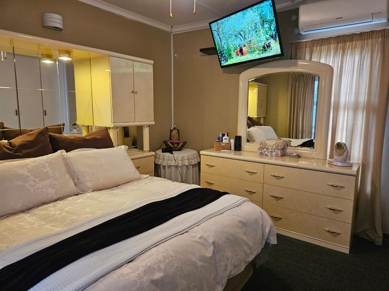 A bedroom featuring built-in cabinetry, wall-mounted air conditioning, and neutral wall finishes, offering a functional space with potential for modern updates.