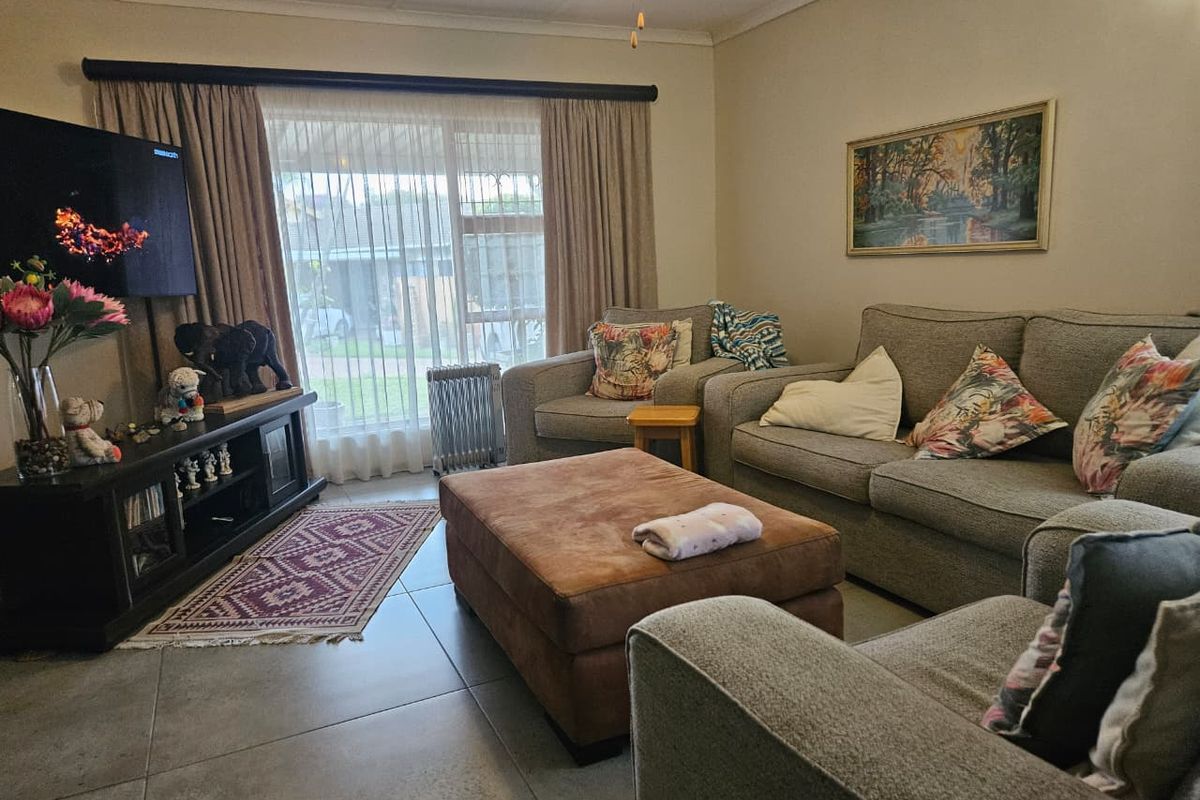 A comfortable living room featuring large sliding glass doors, tiled flooring, and a ceiling fan, providing a functional and well-lit space.